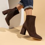 Tronchetti donna in suede marrone con tacco 9 cm, indossati su fondo neutro con jeans arrotolati - Cavallini